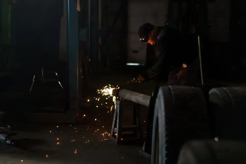 Sparks flying from a frame weld in a dimly lit workshop
